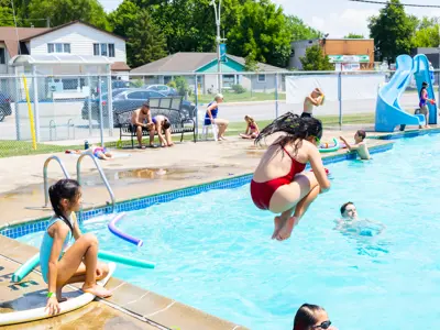 Children cannonballing into the outdoor pool.
