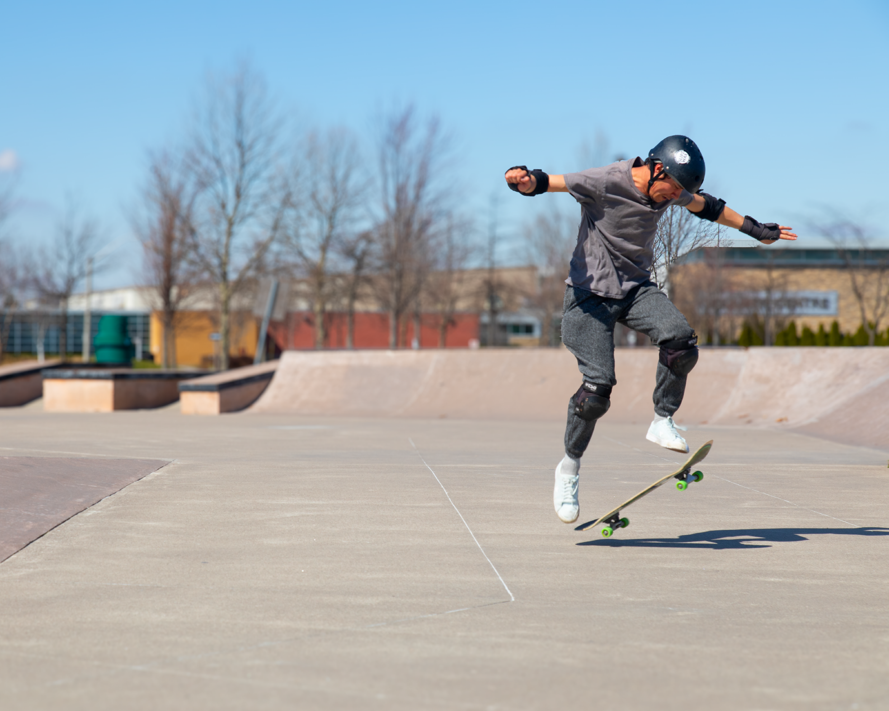 Skateboarder performing a jump trick at an outdoor skate park.