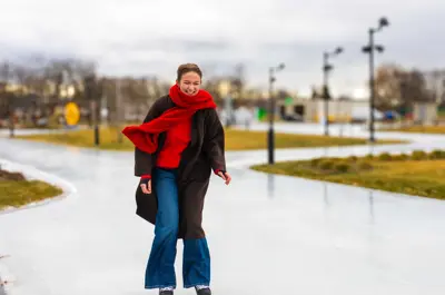 A person skates along an outdoor ice path on a cloudy day.